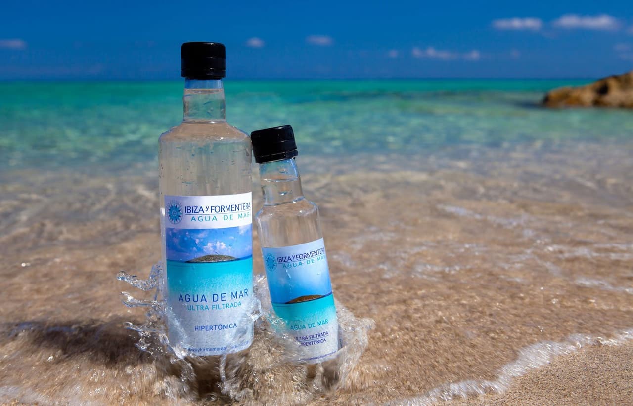Two bottles of water sitting in the gentle waves of a Mediterranean beach