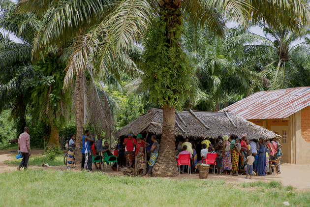 People gather under a hut in Baringa village
