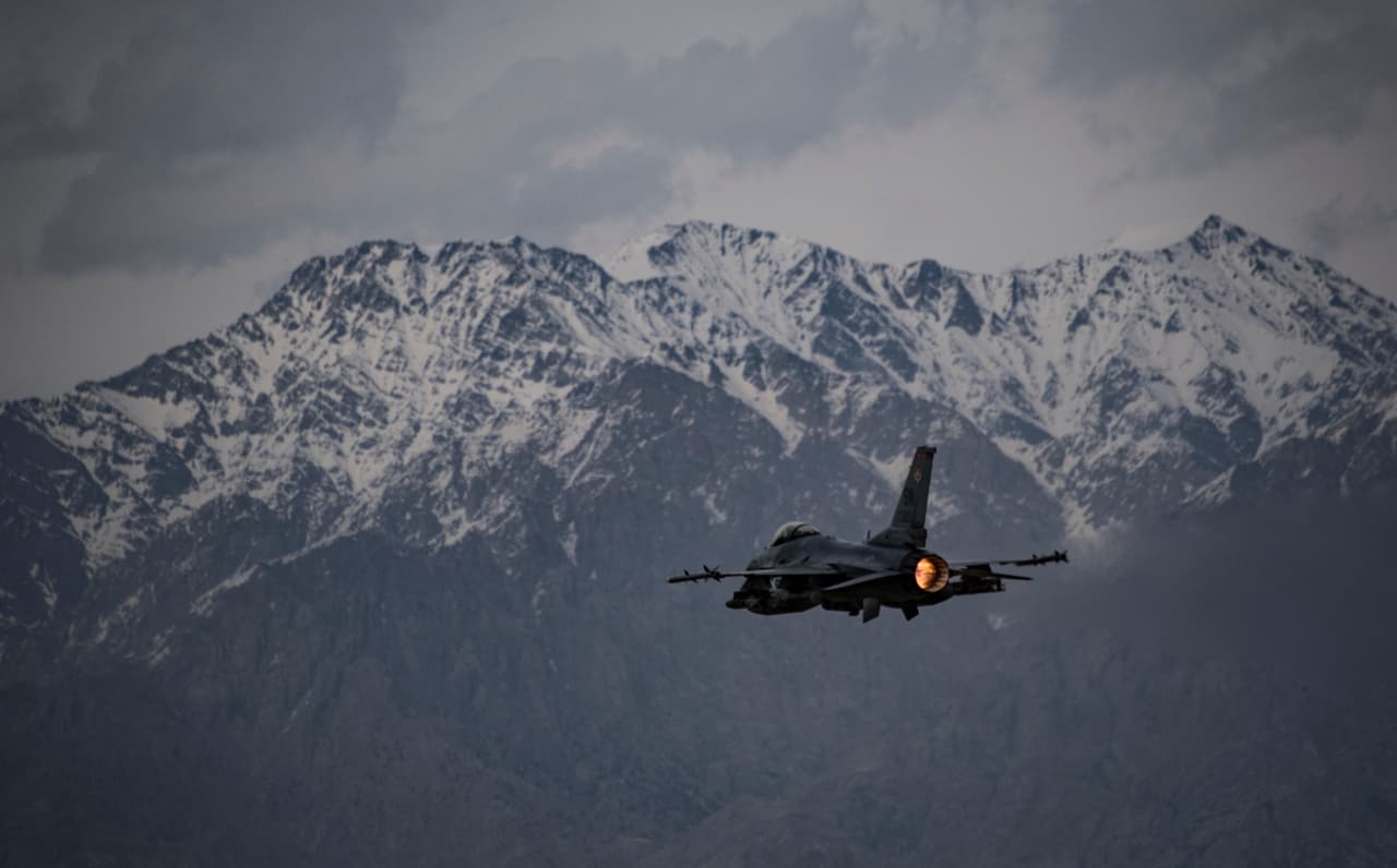 A fighter jet flying past snow-capped mountains