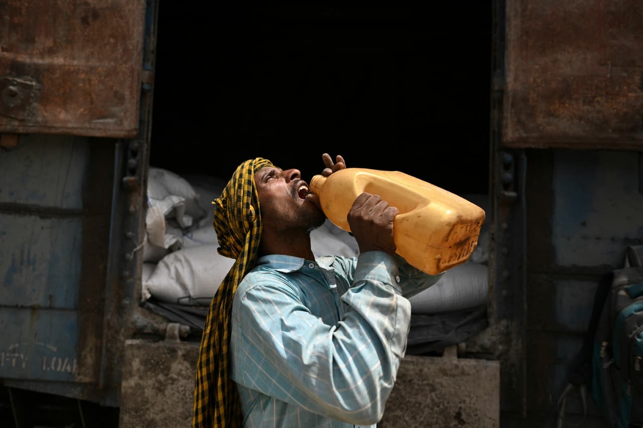 A worker drinks water during a break from loading sacks of wheat on a freight train at Chawa Pail railway station in Khanna, Punjab state, on 19 May