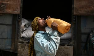 A worker drinks water during a break from loading sacks of wheat on a freight train at Chawa Pail railway station in Khanna, Punjab state, on 19 May