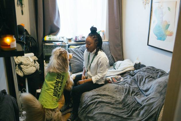 Lauren sits on her bed with her service dog Harley