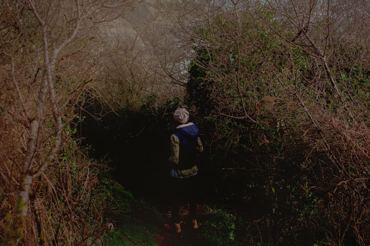 An anonymous woman walks through a woods with her back to the camera