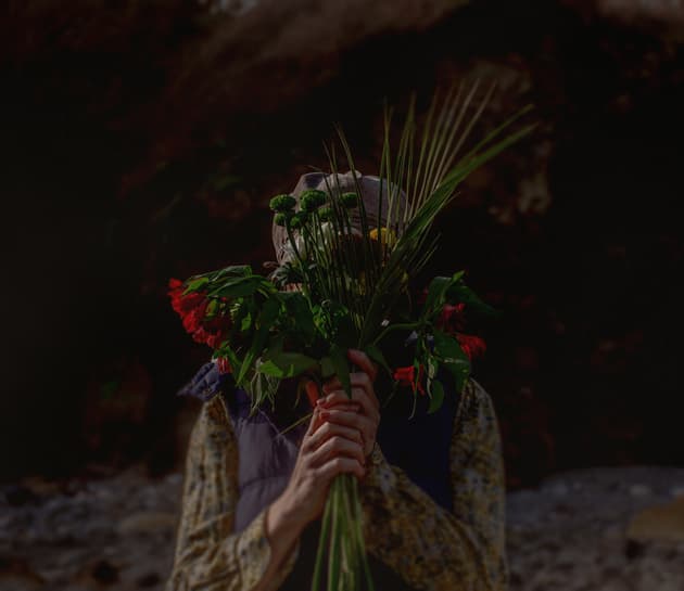 An anonymous woman covers her face with a large bunch of flowers