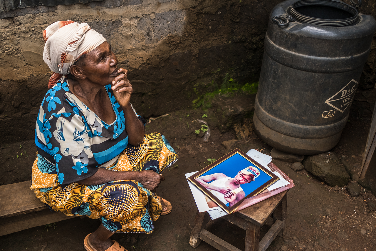 Alice sits next to a photo of her son, Bernard Murigi Wanginye, who was allegedly killed by Del Monte guards. She has been waiting four years for the trial of the men charged with her son's murder