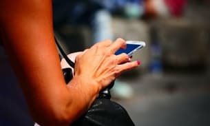 A woman checks her SMS messages and emails on a smartphone