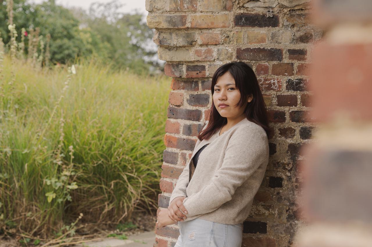 Julia Quecaño Casimiro stands against a wall, looking at the camera