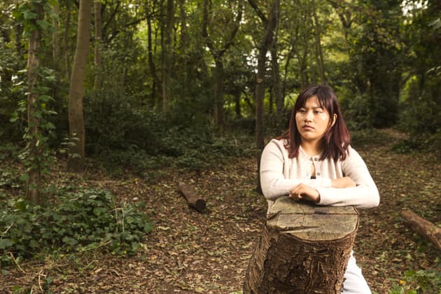Julia Quecaño Casimiro leans on a tree stump in a wood