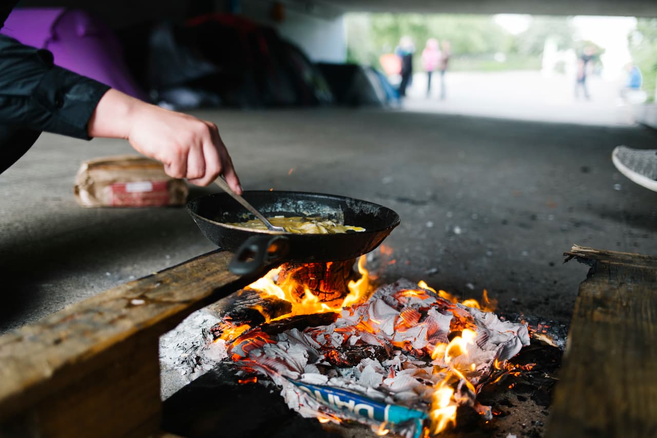 A homeless person cooks food over a makeshift fire in an underpass in Milton Keynes