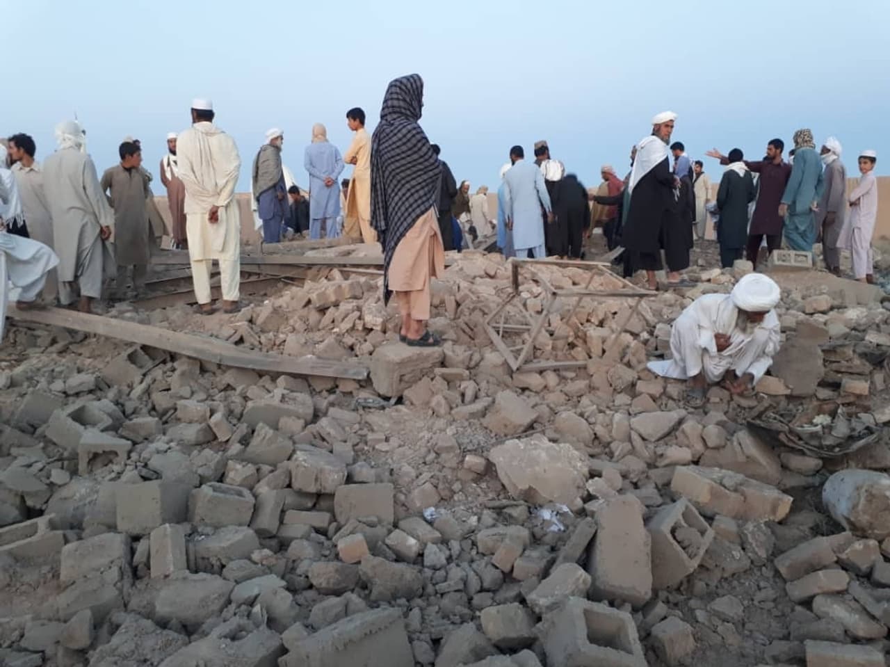 People stand on a levelled building at daybreak
