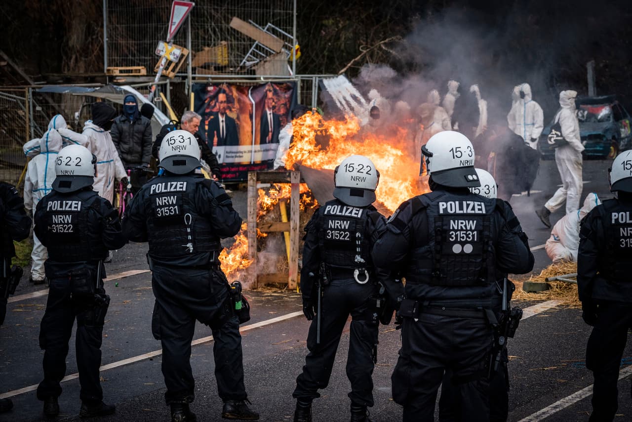 Riot police stand in front of burning barricades as activists stage a protest in Lützerath