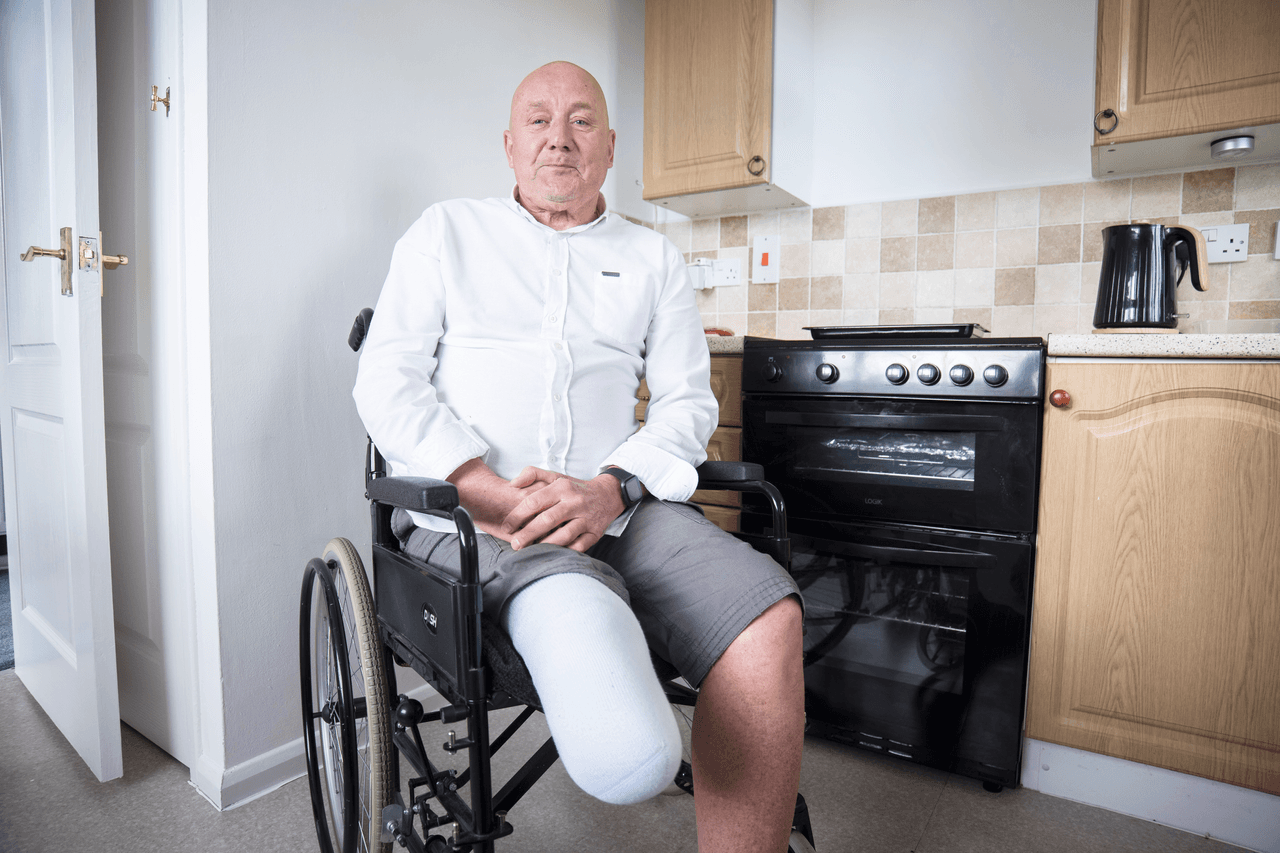 A man in a wheelchair with a prosthetic leg in his kitchen