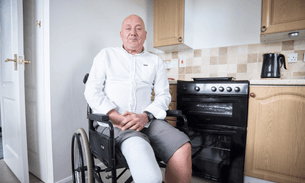 A man in a wheelchair with a prosthetic leg in his kitchen